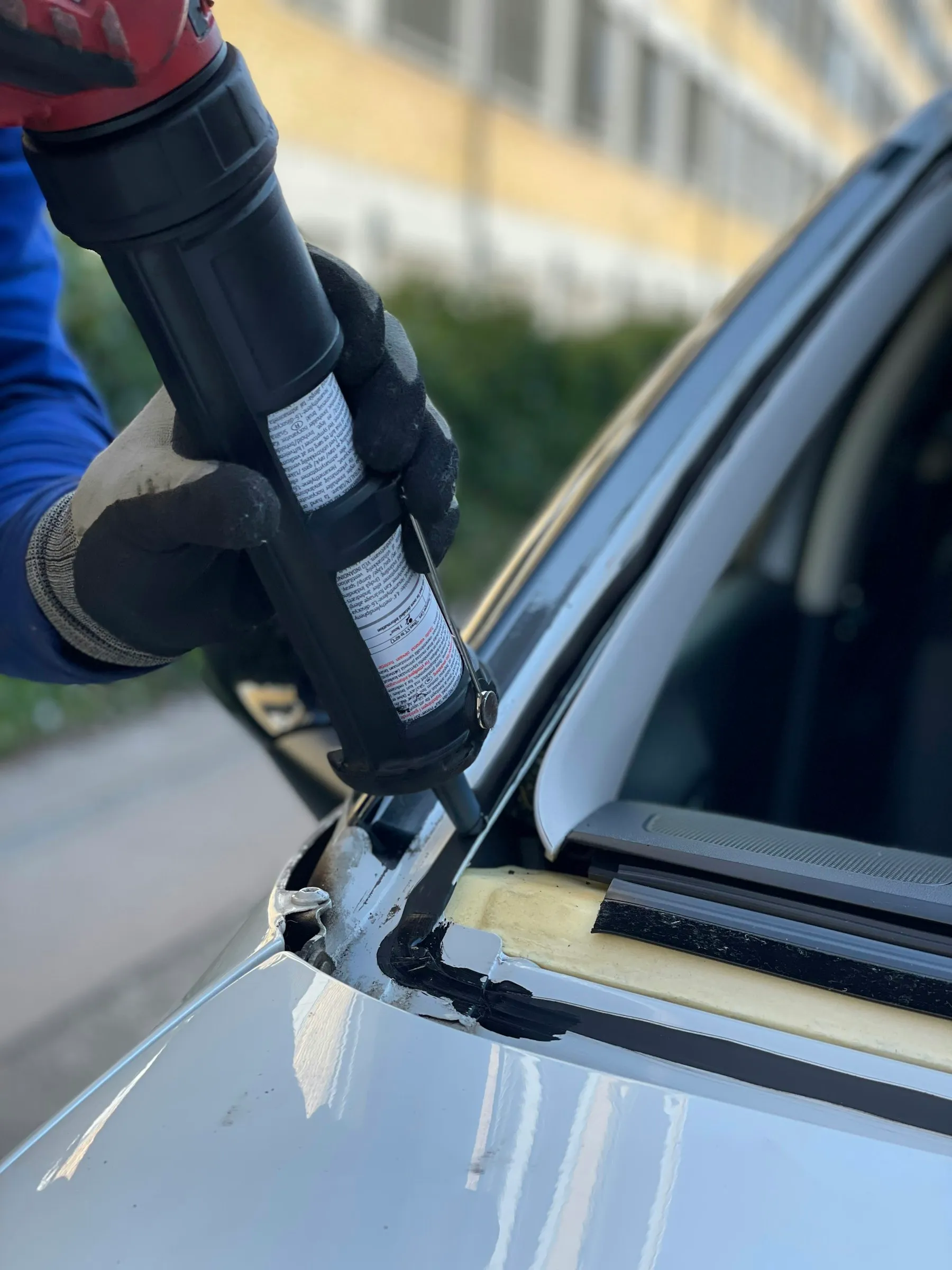 Auto glass technician preparing urethane adhesive for a windshield replacement