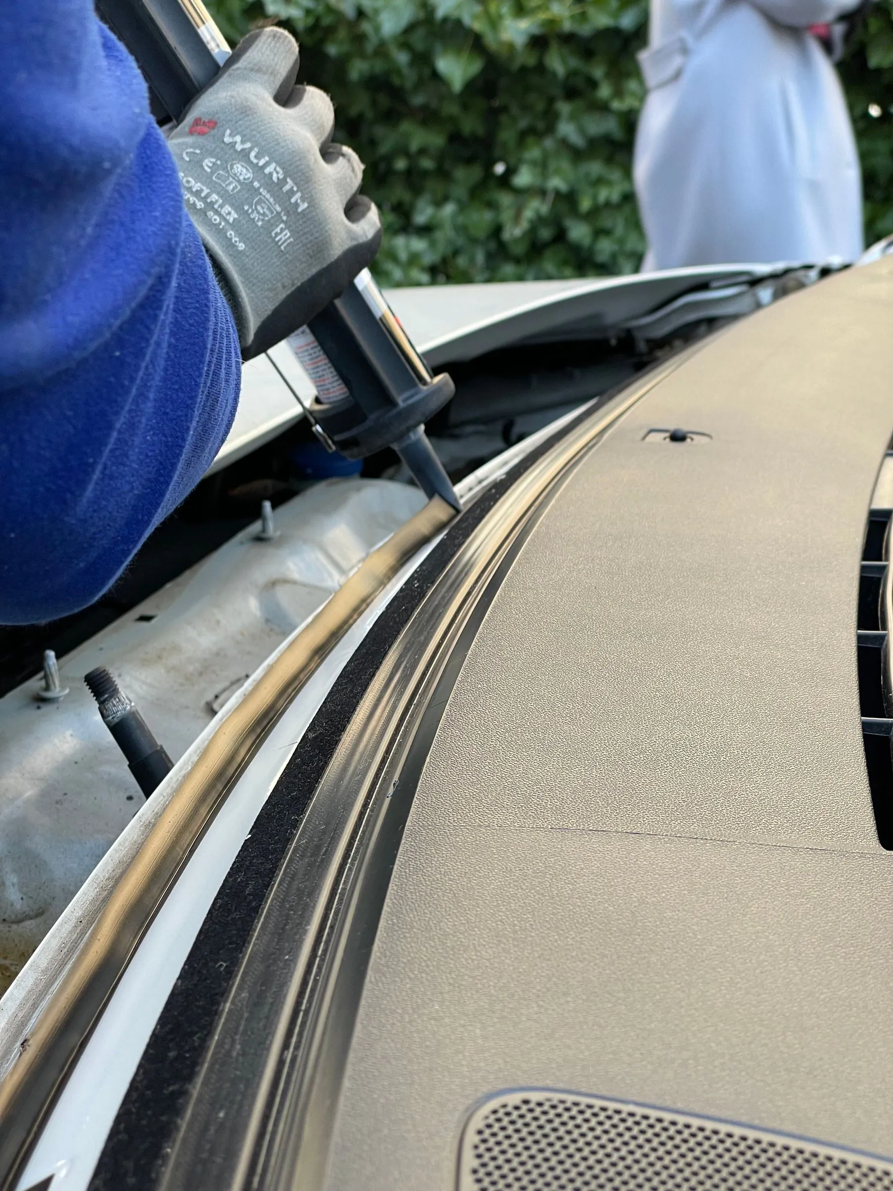 Gloved hands sealing the edge of a windshield