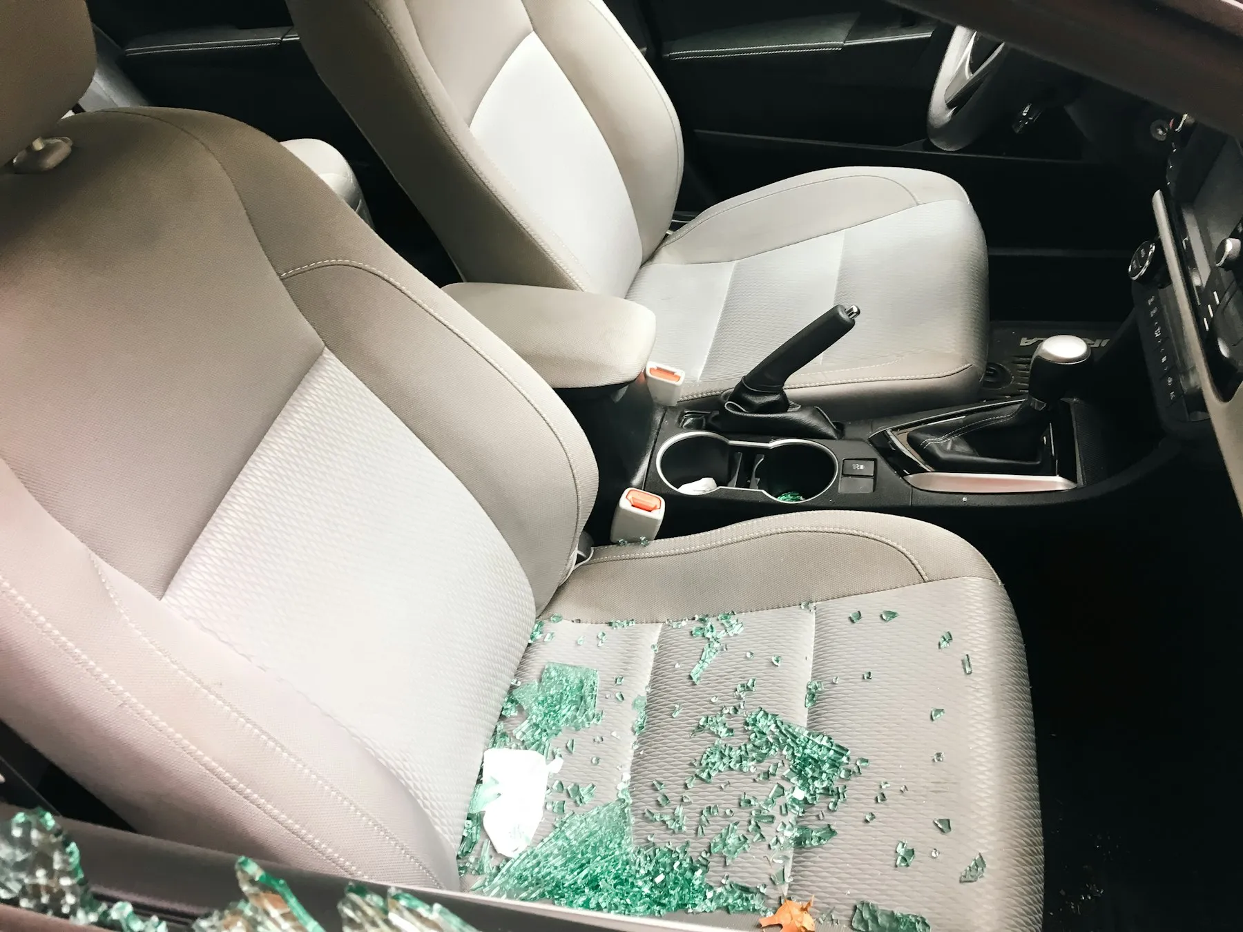 Tempered glass fragments scattered across car seats after a side window broke